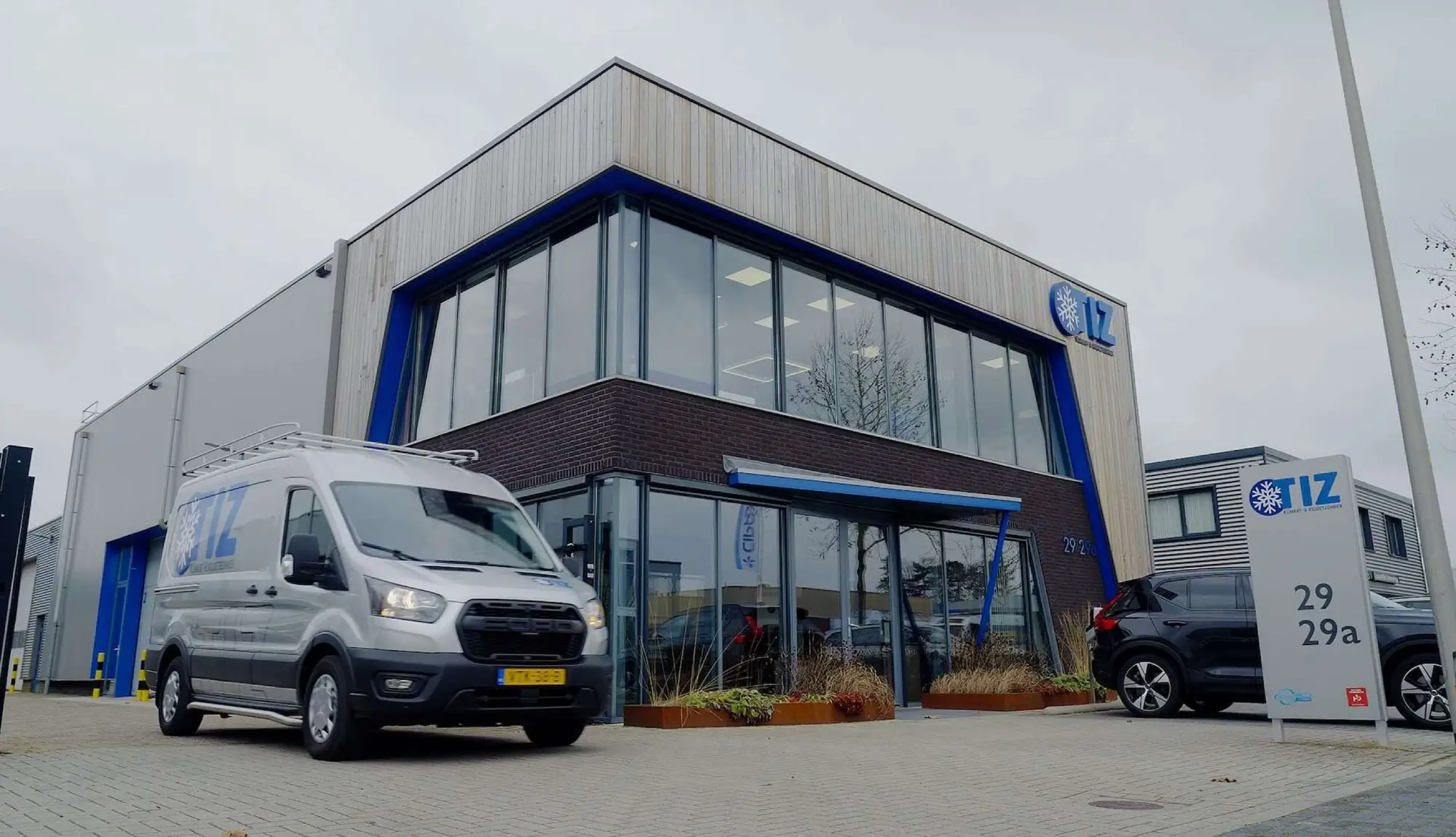 Bedrijfspand van TIZ in Rijssen met servicebus voor de deur en gevelreclame op nummer 29
